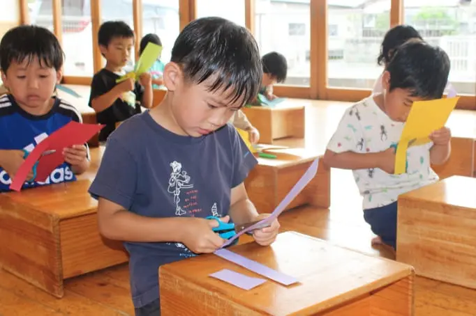 ハサミで紙を切っている子どもたち