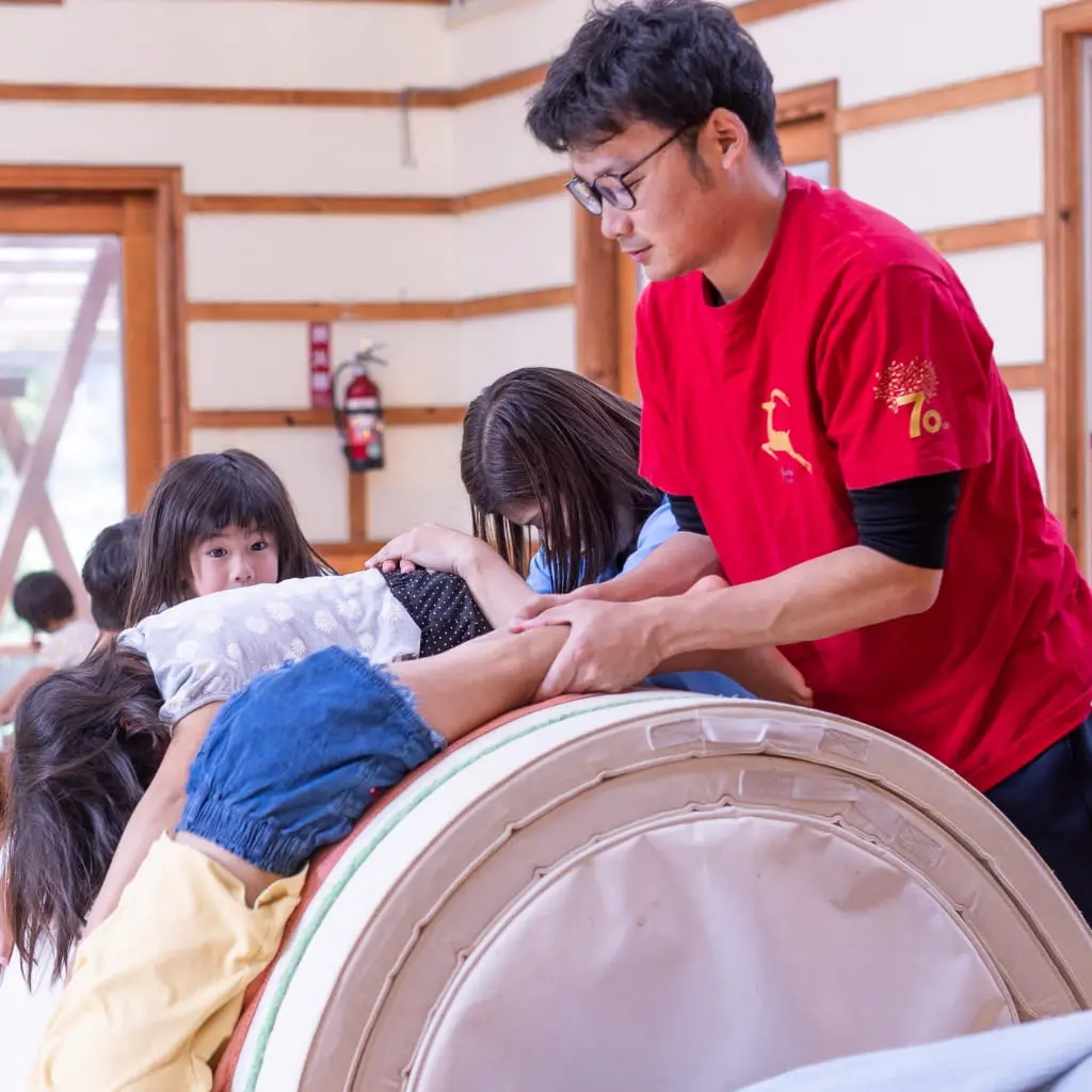 子供とロールマット運動をする保育教諭