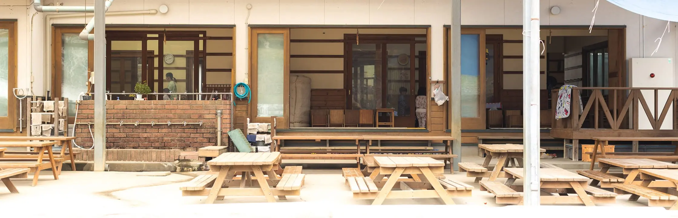 木造の園舎とベンチが並ぶ保育園の外観